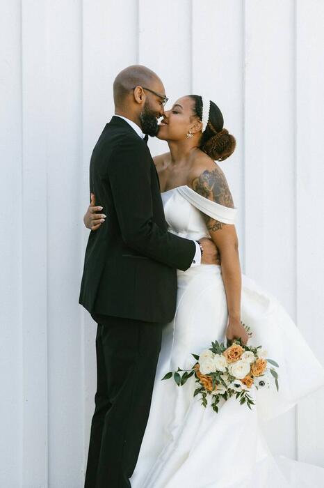 Bride and groom against a white wall